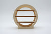 A minimalist circular wooden shelf with three horizontal slats and a matching rectangular base, shown against a seamless light gray studio background.